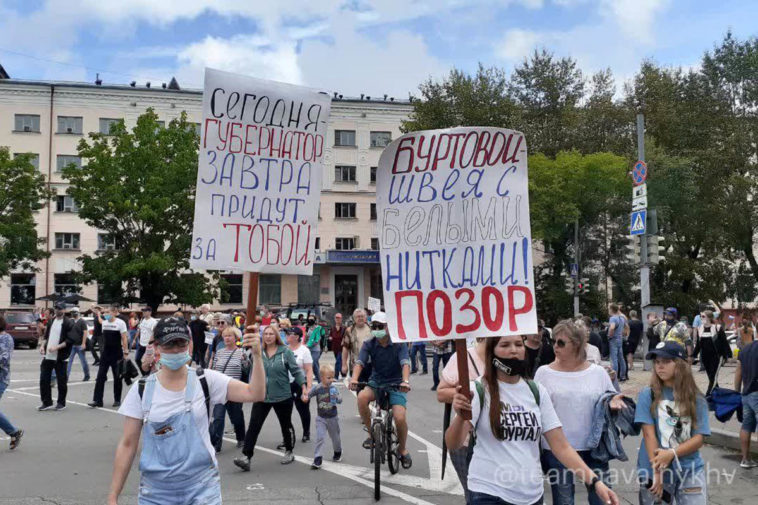 Люди несут плакаты на митинге