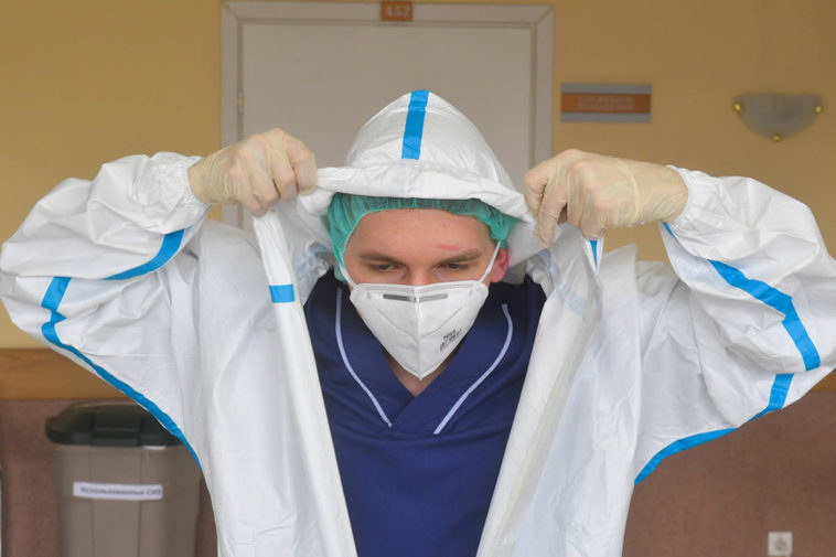 Врач снимает защитный костюм после работы с больными коронавирусом