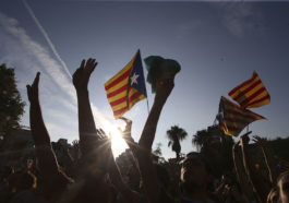 Толпа с флагом Каталонии поднимает руки