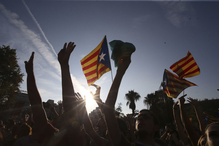 Толпа с флагом Каталонии поднимает руки