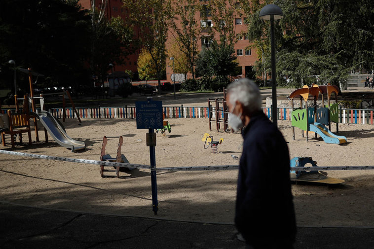 Мужчина в защитной маске возле закрытой детской площадке в Мадриде, октябрь 2020 года