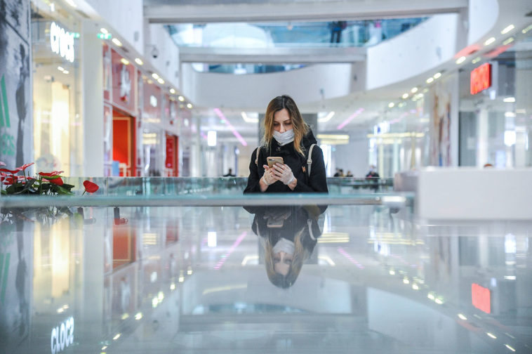 Девушка смотрит в телефон в торговом центре