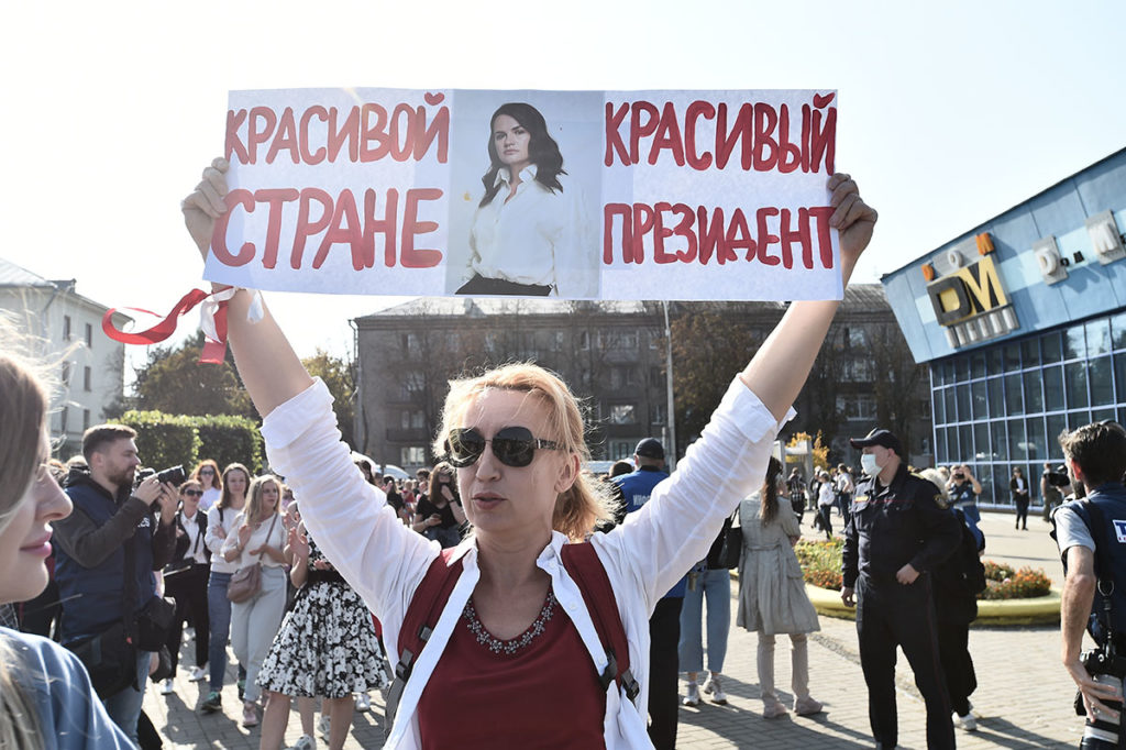 Женщина держит плакат на митинге