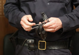 Полицейский держит наручники