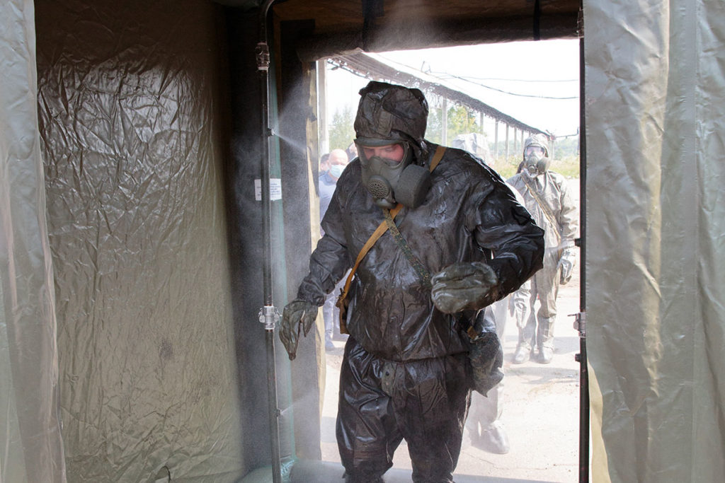 Сотрудник Федерального экологического оператора в защитном костюме проходит дезинфекцию на выходе с территории бывшего химкомбината "Усольехимпром"
