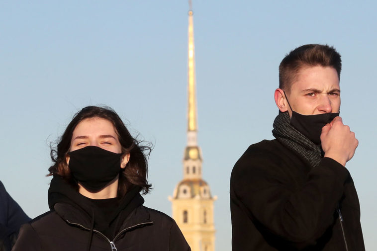 Люди в масках на фоне здания Адмиралтейства в Санкт-Петербурге