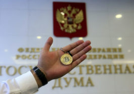 Монета биткоина на фоне Госдумы