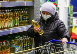 Женщина покупает подсолнечное масло в магазине