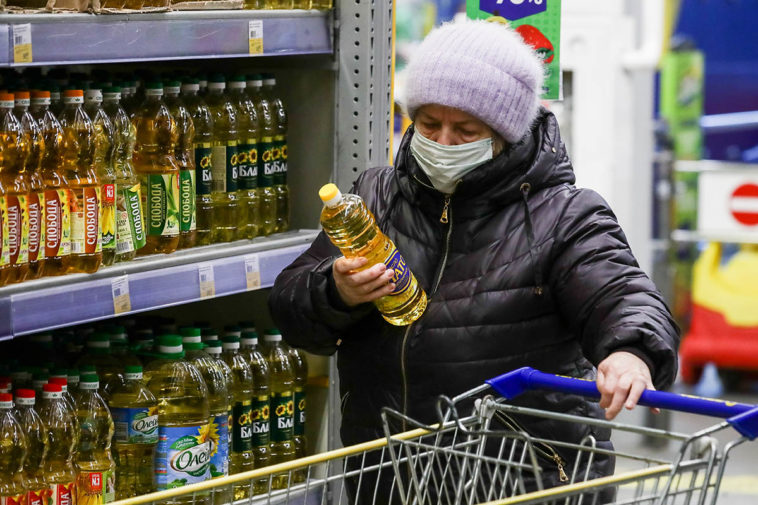 Женщина покупает подсолнечное масло в магазине