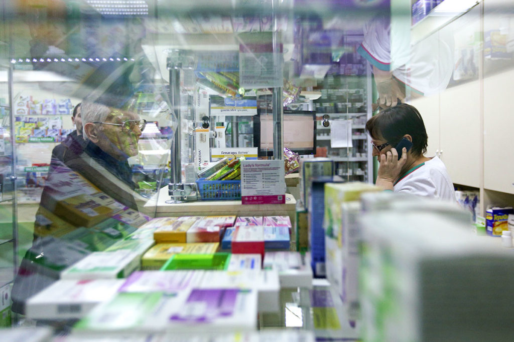 Женщина покупает лекарства в аптеке
