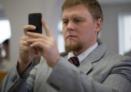 Журналист Сергей Степанов держит в руках смартфон
