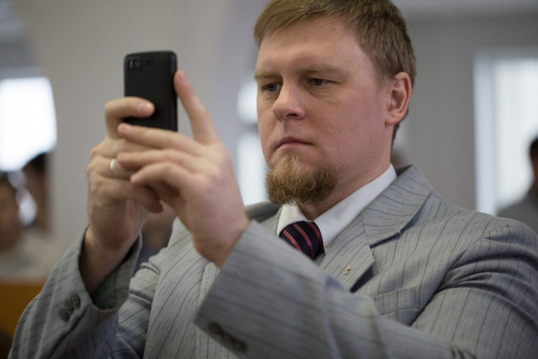 Журналист Сергей Степанов держит в руках смартфон