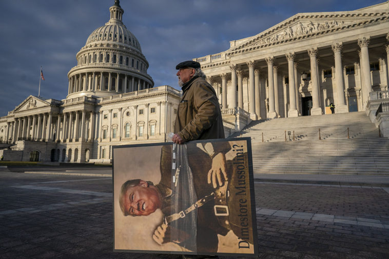 Анти-Трамповский активист с портретом Трампа на фоне здания Конгресса США в Вашингтоне