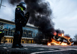 Полицейский Нидерландов на фоне горящей машины