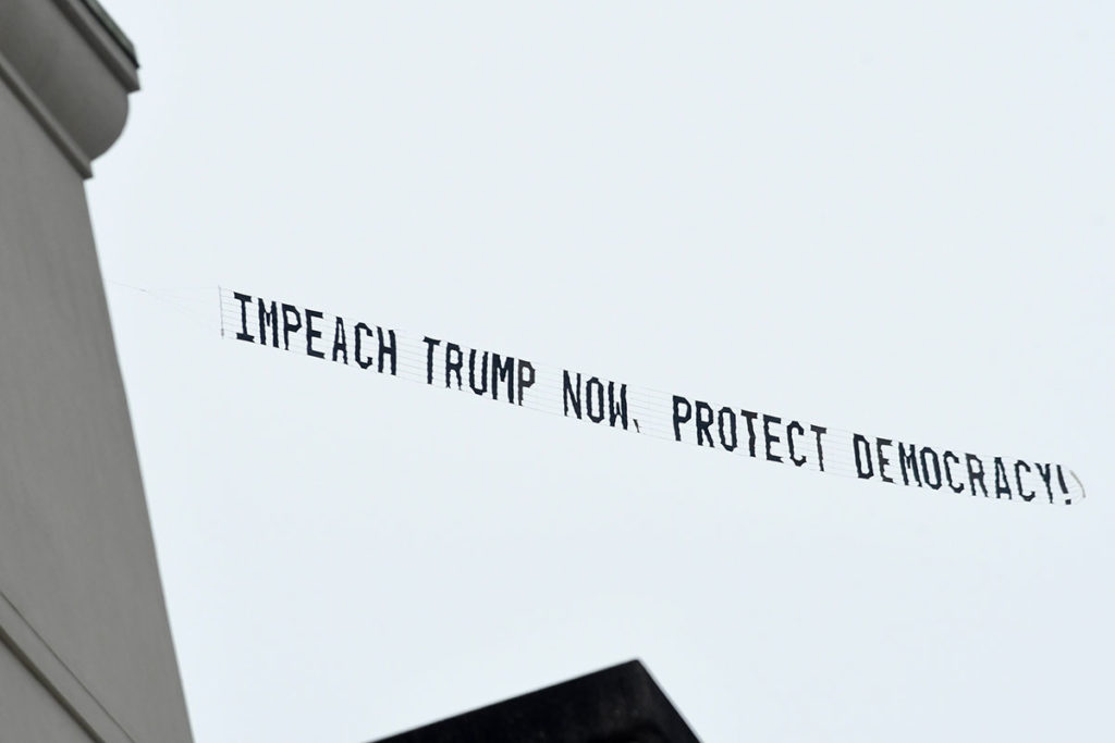 Надпись «Объявите импичмент Трампу сейчас, спасите демократию», привязанная к самолету, в небе над Орландо
