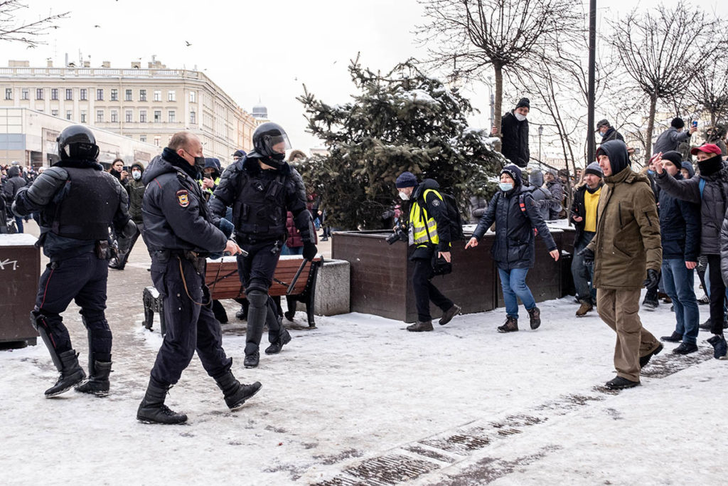 Полицейский направляет табельное оружие в сторону протестующих 31 января в Петербурге