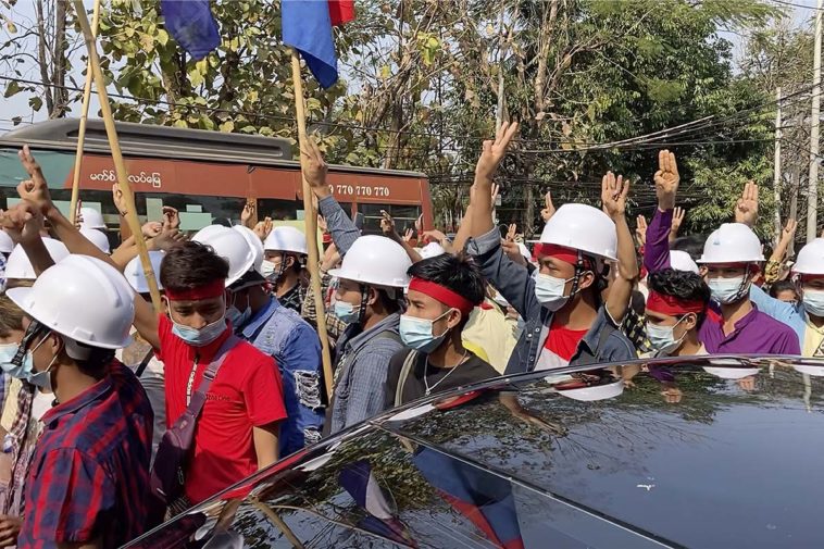 Протестующие в касках демонстрируют трехпалый салют во время марша в Янгоне, Мьянма