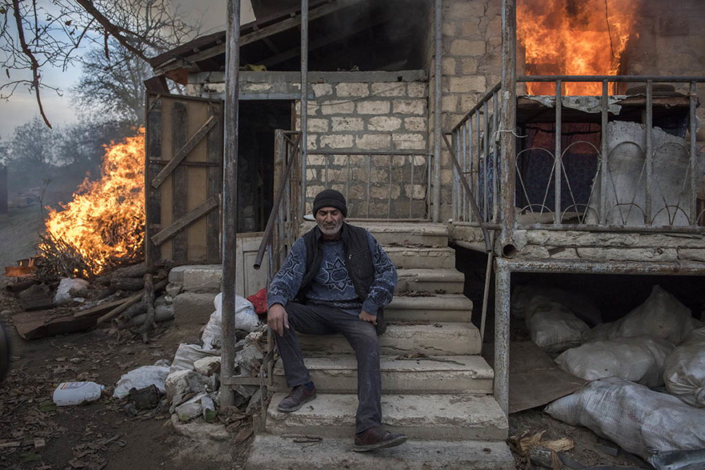 Местный житель рег сидит у горящего дома в селе Карегах Нагорного Карабаха. Некоторые жители сожгли свои дома перед отъездом.