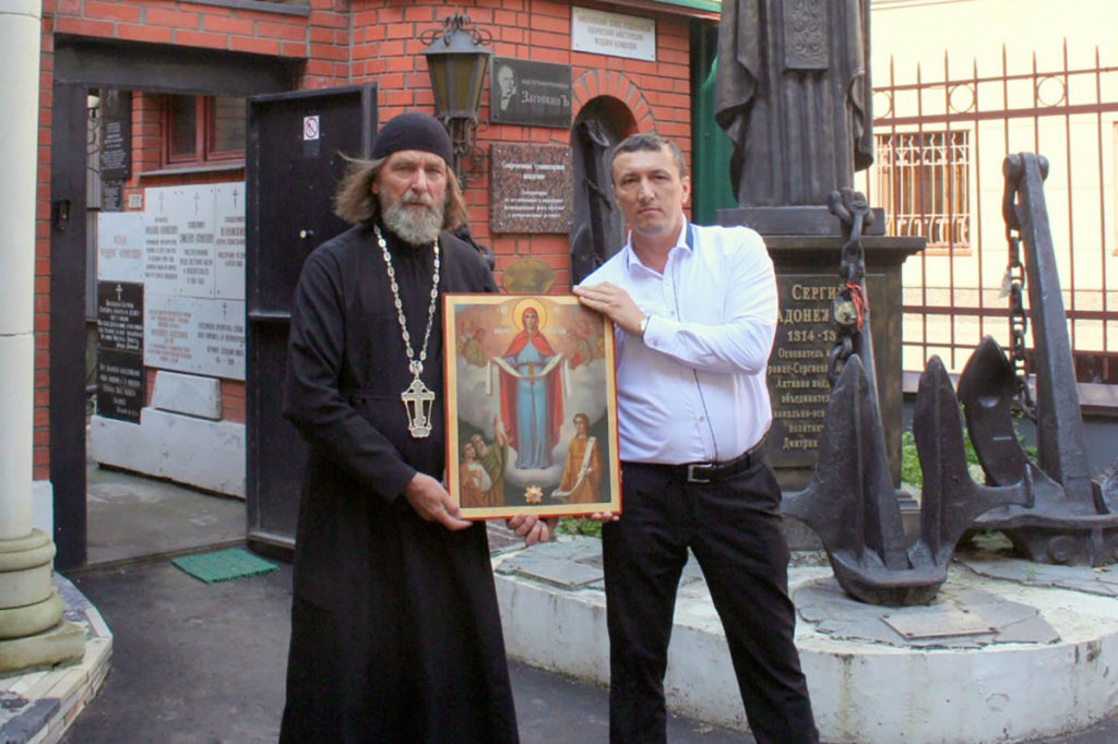Евгений Королев и батюшка держат икону