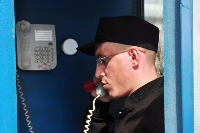 Заключенный разговаривает по телефону в колонии
