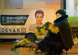 Продавщица цветов на фоне рекламы на микроавтобусе штаба кандидата в президенты Ксении Собчак накануне праздника 8 марта
