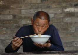Пожилой мужчина ест лапшу. Пекин, Китай