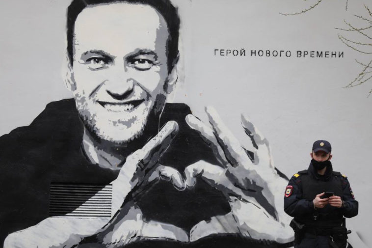 Полицейский на фоне граффити с Навальным