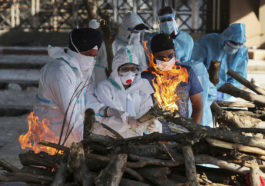 Члены семьи человека, умершего от COVID-19, зажигают погребальный костер в крематории