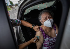 Пожилую женщину вакцинируют от COVID-19 препаратом AstraZeneca, Бразилия