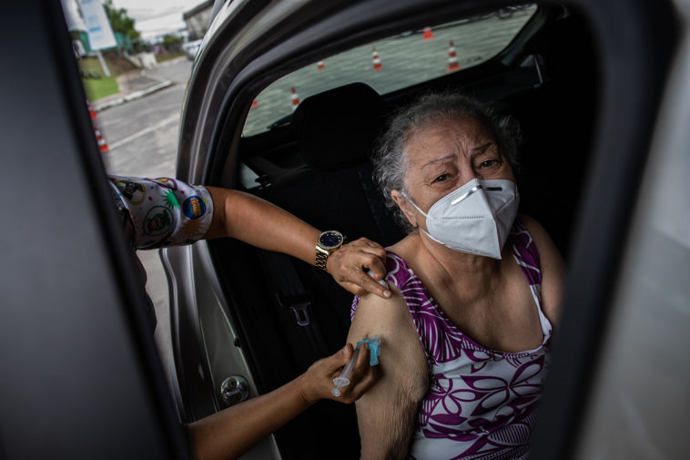 Пожилую женщину вакцинируют от COVID-19 препаратом AstraZeneca, Бразилия